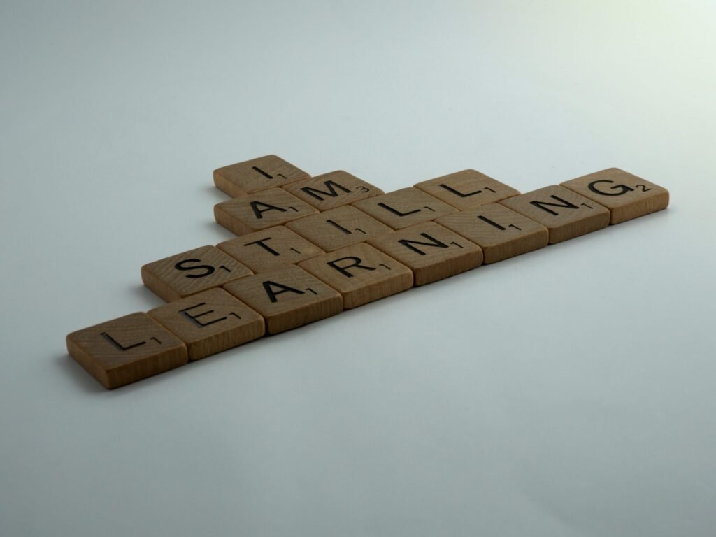 Wooden letter tiles spelling I am still learning, on a pale grey surface